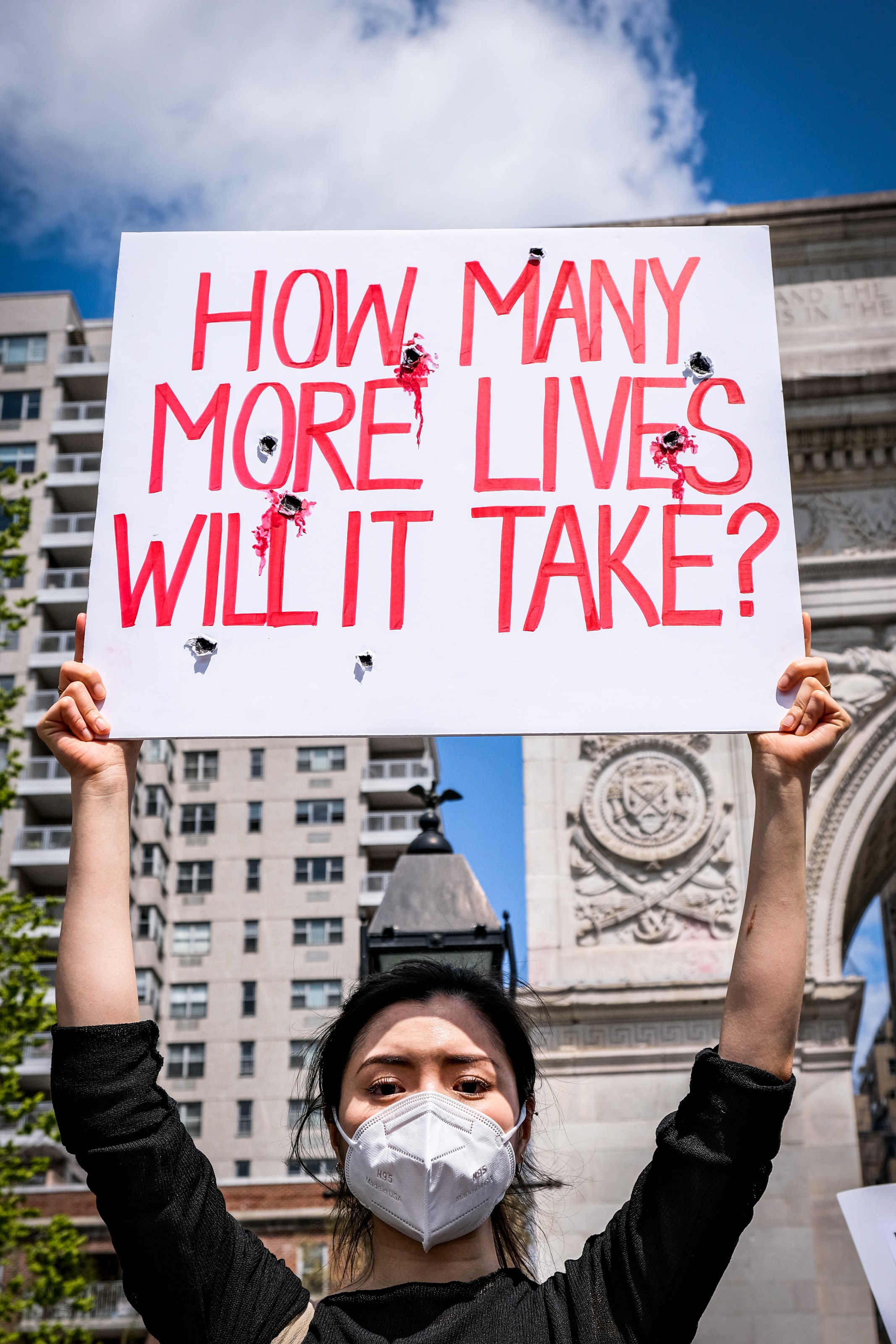 Man holding sign that reads "How man more lives will it take?"