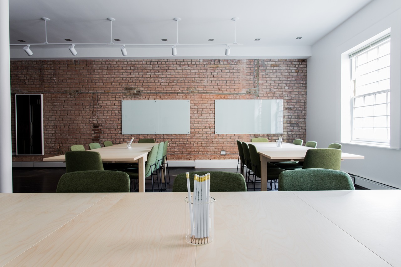 Empty office space with clear desks and a brick wall