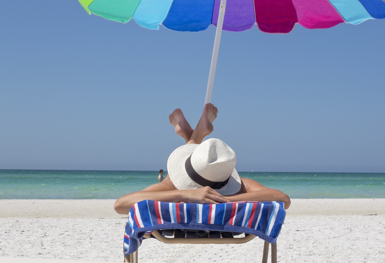 person lying on a beach chair under an umbrella