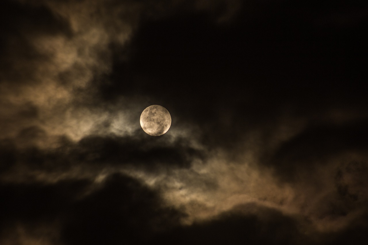 moon against a night sky, behind clouds