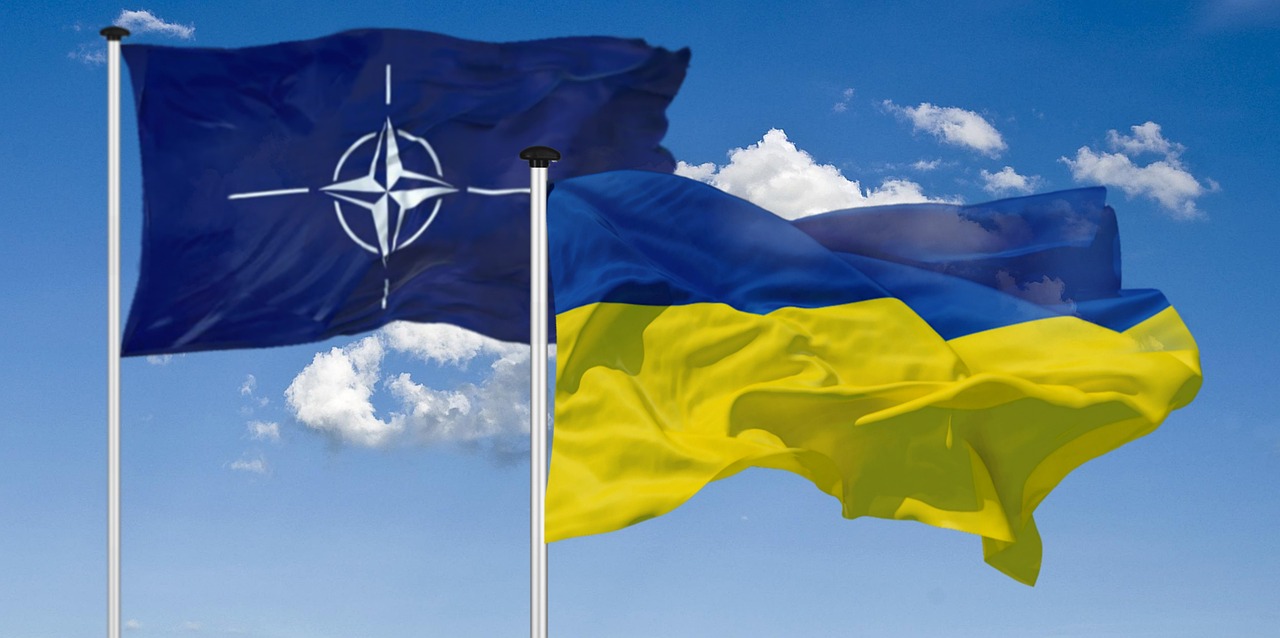 NATO and Ukraine flags on flag poles flying in the sky