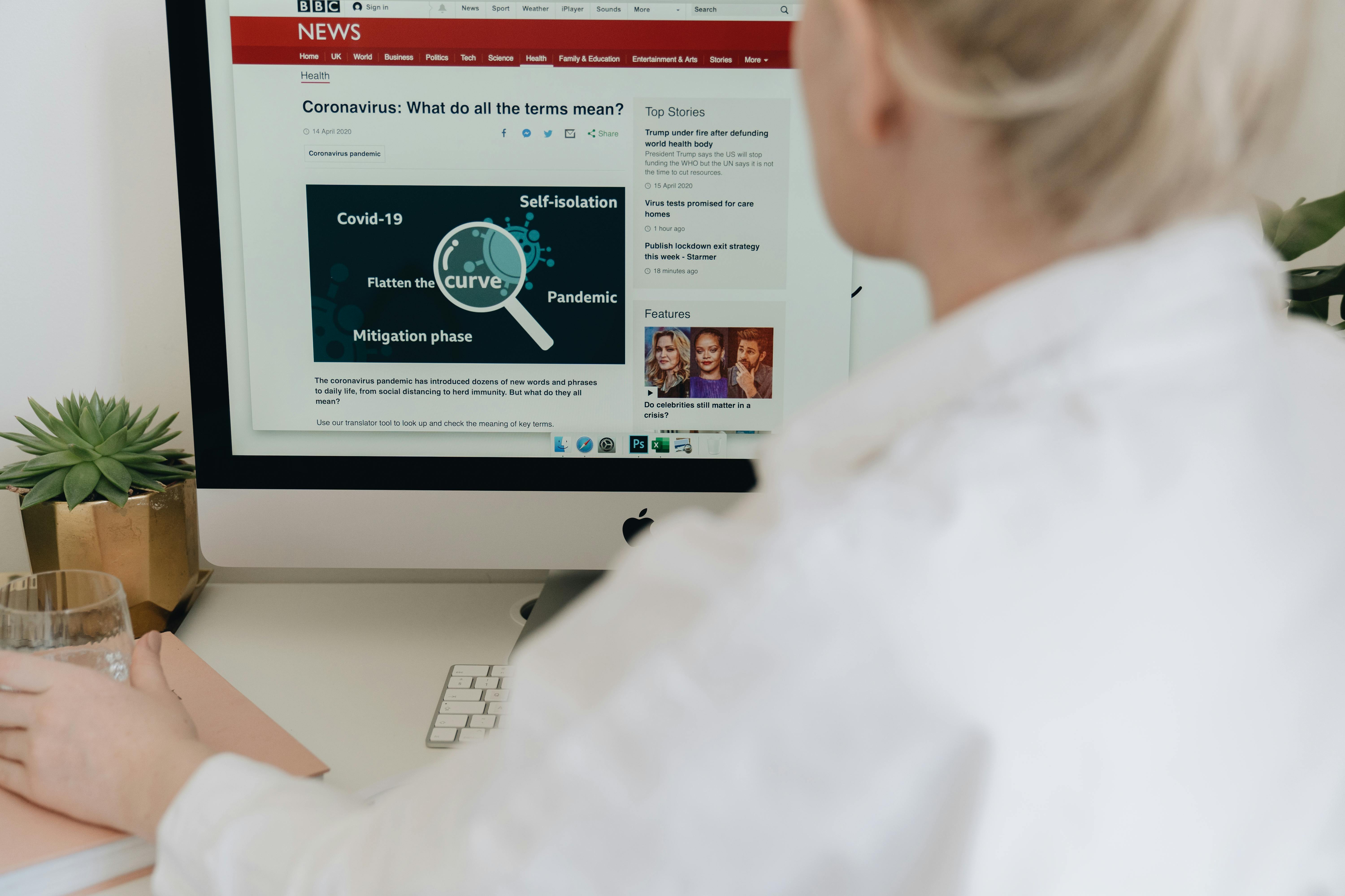 woman sitting at a computer with a BBC News page on a computer screen