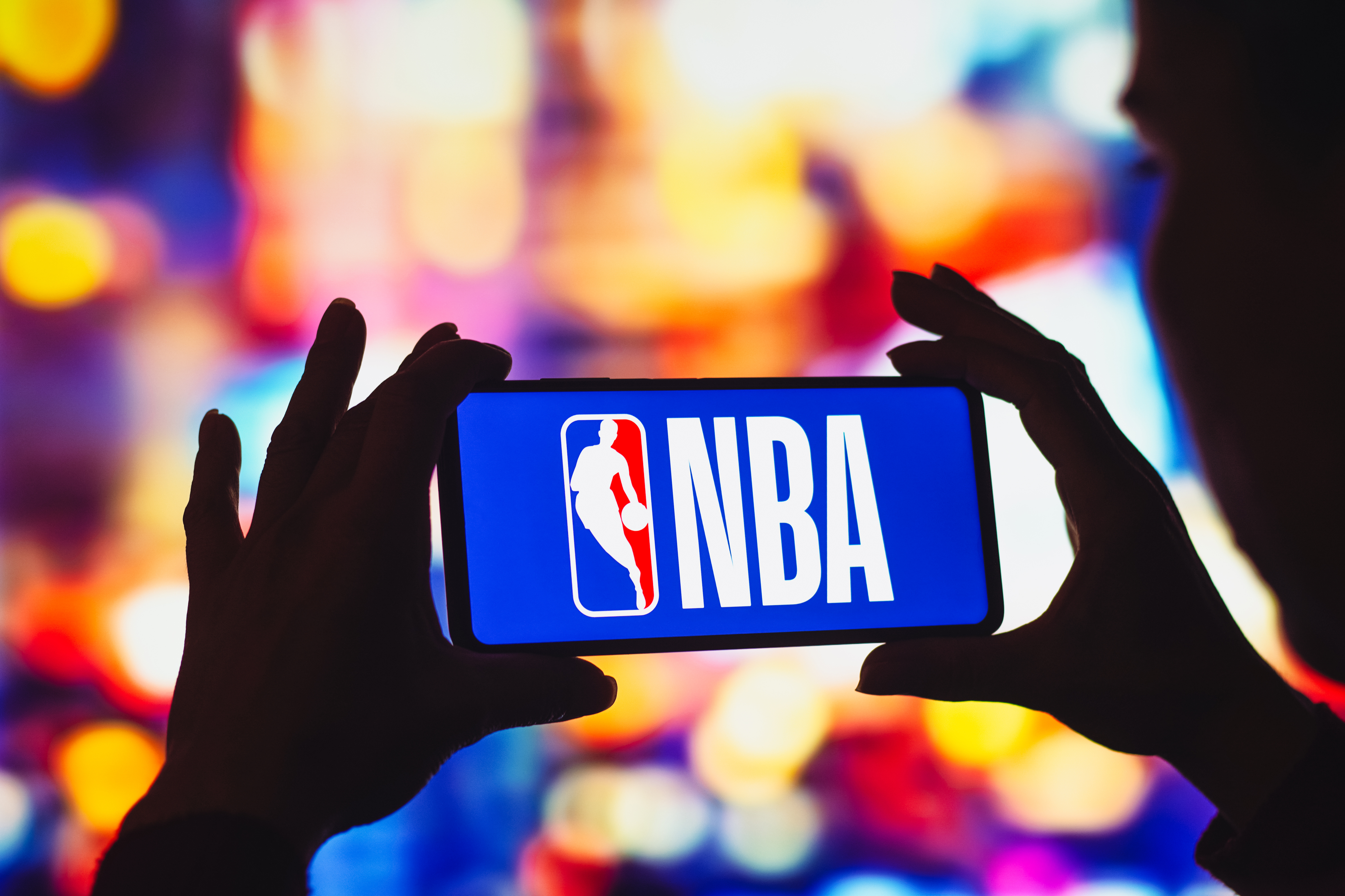 person holding a phone with a NBA logo on the screen