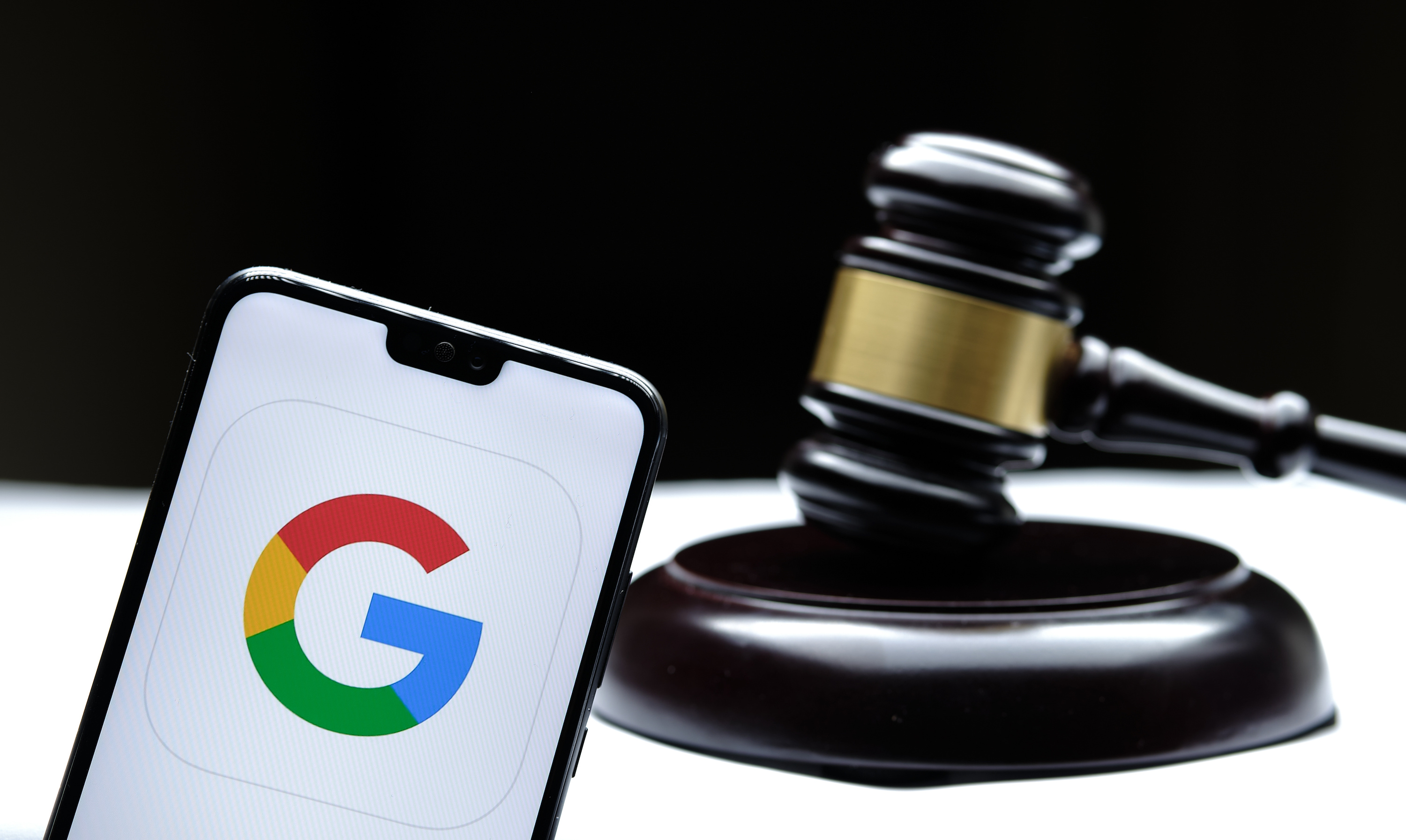 Google logo on a smartphone with a judge gavel in the background