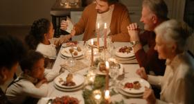 Family gathered at holiday themed dinner table with candles. 