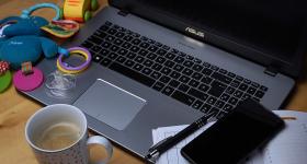 Laptop on a desk with a coffee cup and children's toys to show work-from-home and work-life balance.