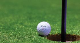 Close up of a golf ball near a hole on the green