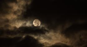 moon against a night sky, behind clouds