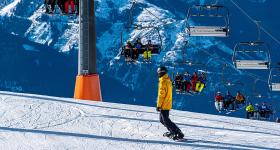 snowboarder on a mountain with a full ski chair lift in the background
