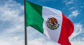 Mexico Flag flying on a flag pole with a blue sky in the backgroun