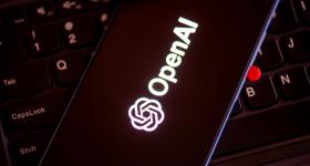 OpenAI logo on a phone screen with a computer keyboard in the background