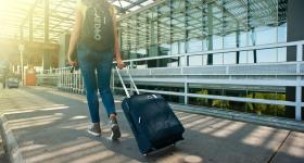 traveler wheeling their luggage outside an airport