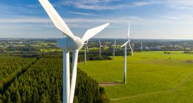 wind turbine with green land and blue skies in the background